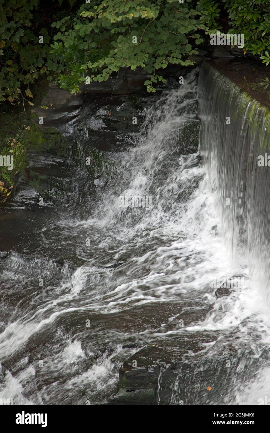Water flowing over a man-made stone waterfall, or weir, being diverted away from Aberdulais waterwheel, Neath, Wales Stock Photo