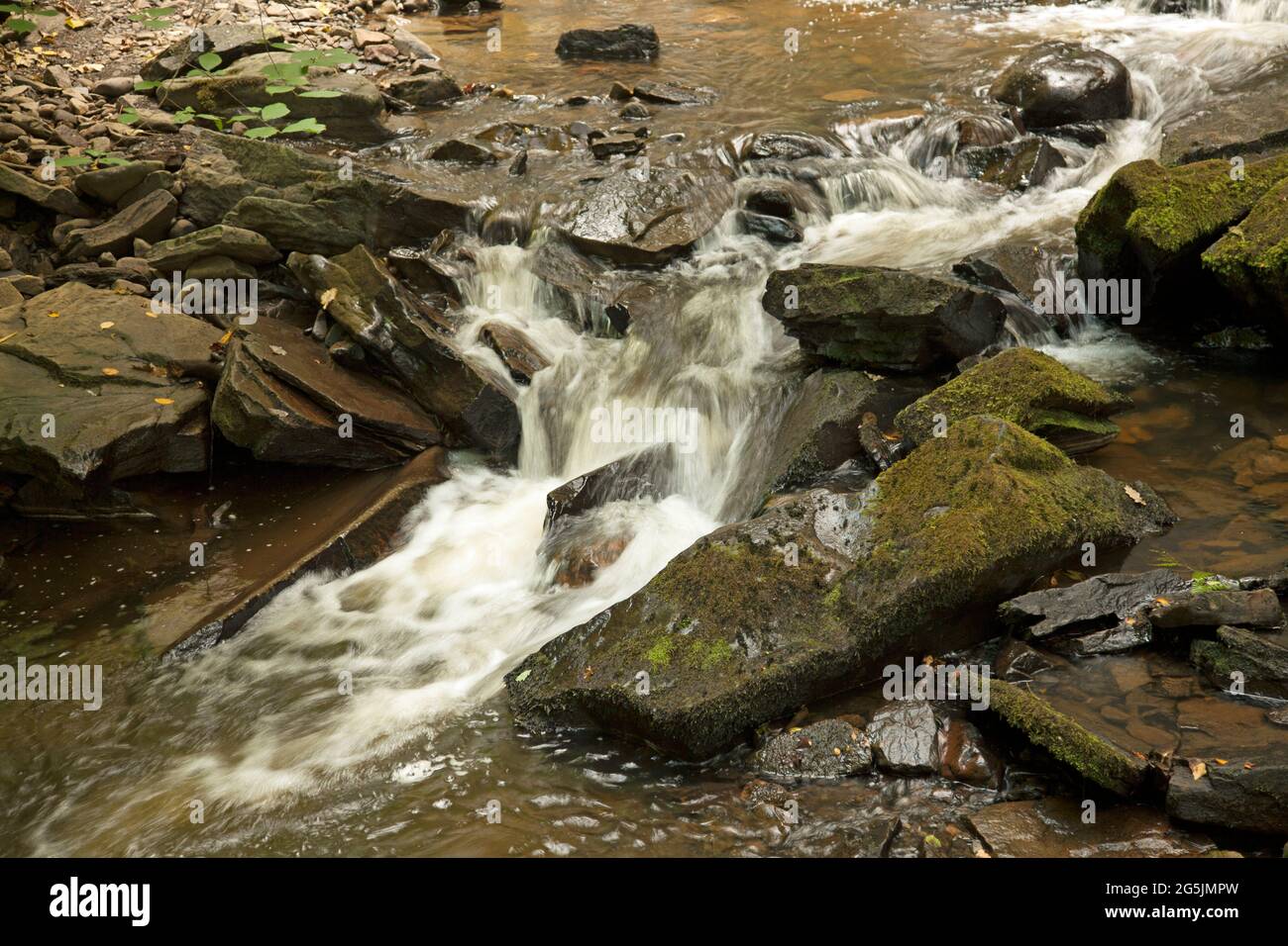 Water flowing over a mini waterfall, Aberdulais, Neath, Wales. Long exposure, to show the motion of the water Stock Photo