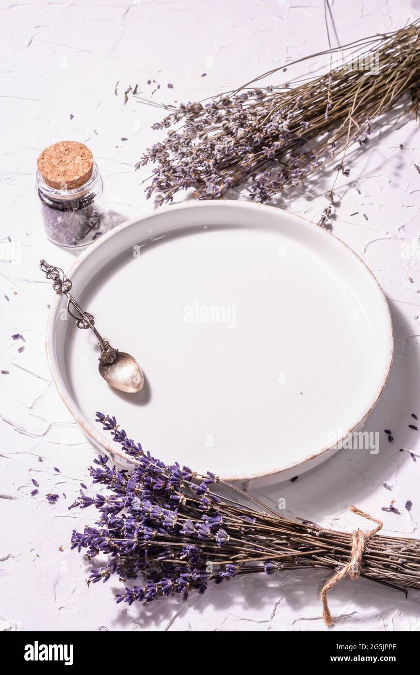 Table setting for a sweet dessert. Plate, vintage silver spoon, lavender  flowers. Modern hard light, dark shadow. White putty background, copy space  Stock Photo - Alamy