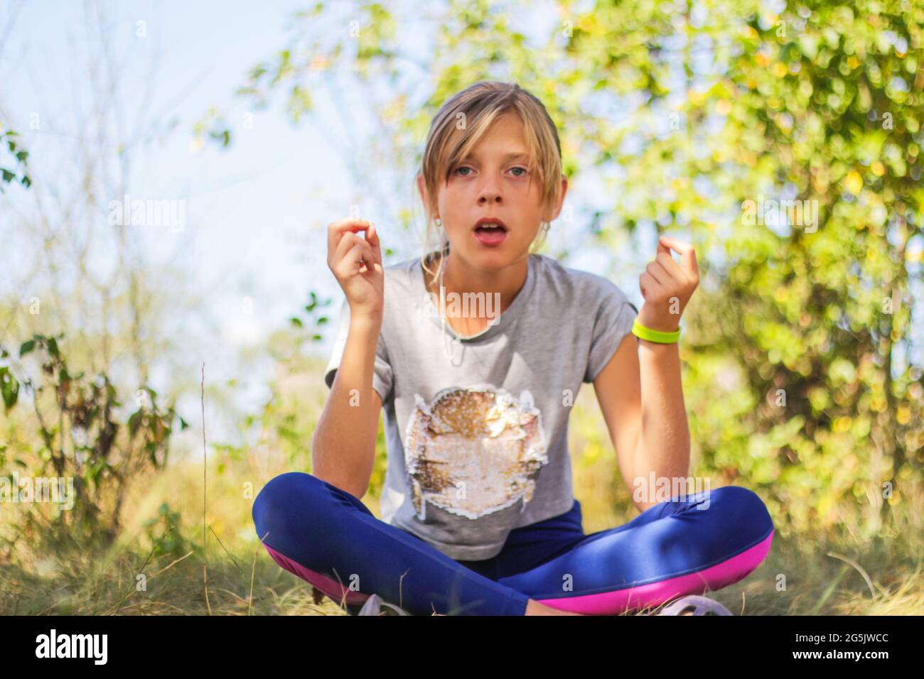Defocus caucasian preteen girl practicing yoga in park, forest, outdoor, outside. Meditation, concentration, mantra. Wellness lifestyle. Portrait of Stock Photo