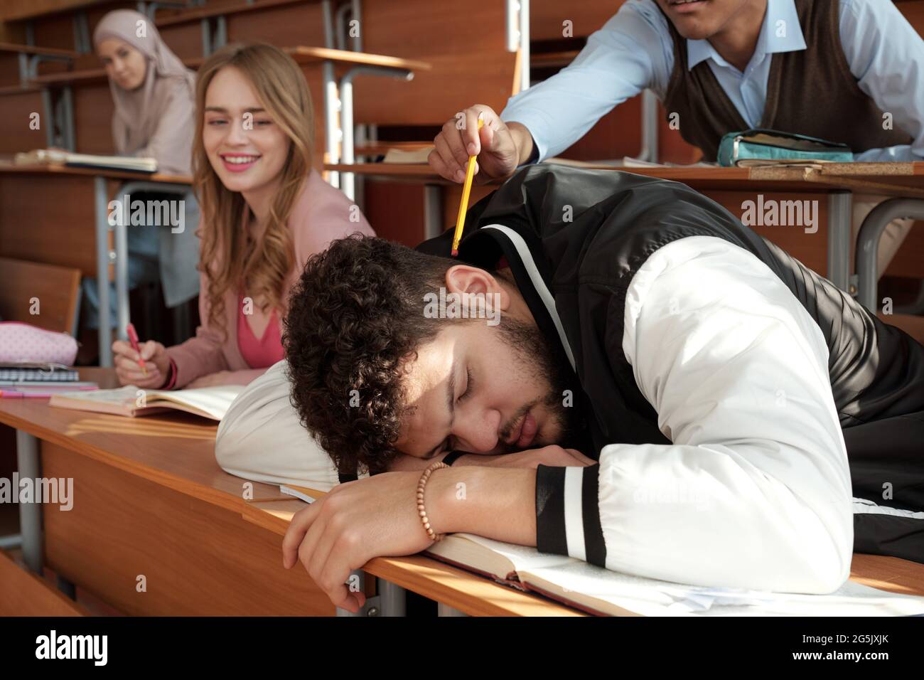 One of students trying to wake up his groupmate sleeping on desk Stock Photo