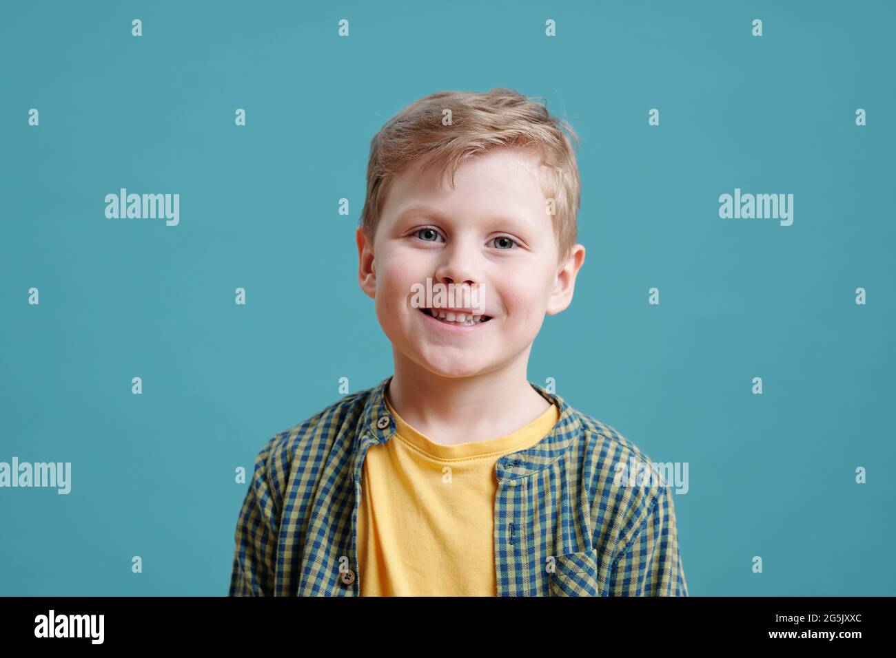 Happy cute little boy looking at you on blue background Stock Photo - Alamy