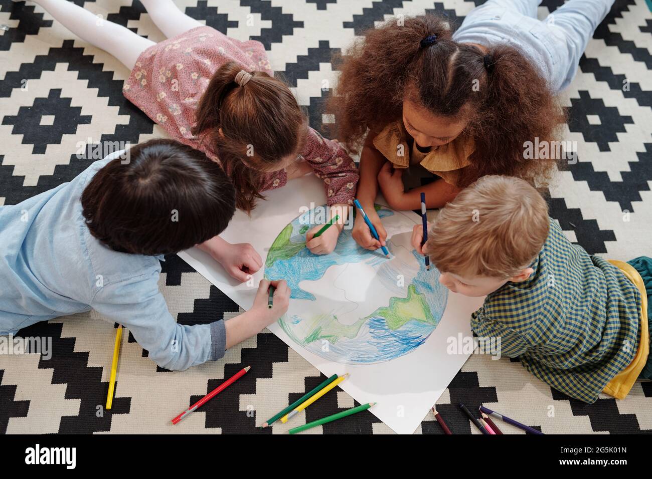 Cute kids drawing planet on large paper while lying on the floor Stock ...