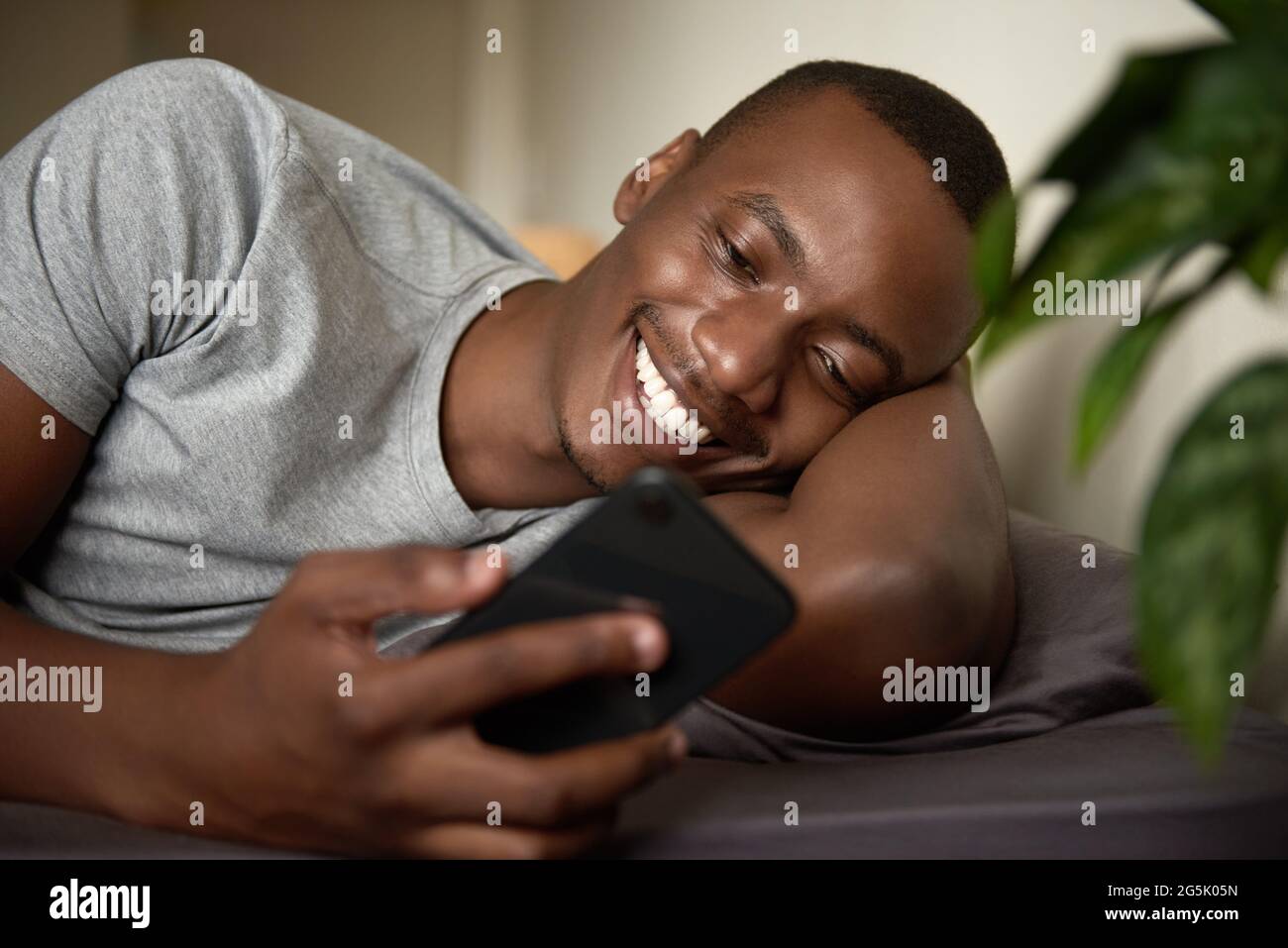 Smiling African man reading a text in bed in the morning Stock Photo