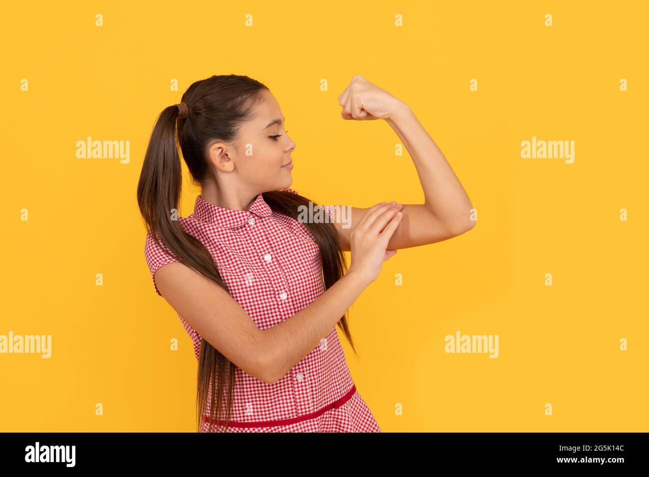 Girl power. Female child flex arm yellow background. Gesture of power and strength. CRL PWR Stock Photo
