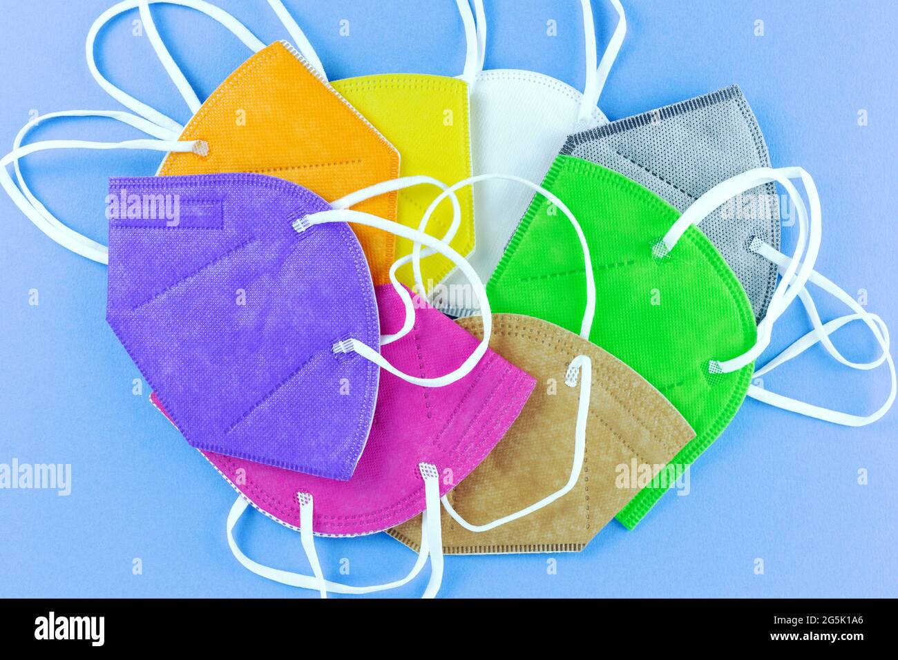 Heap of  different colors face masks respirators on blue background. Top view flat layer. Protection from covid virus during pandemic. Stock Photo