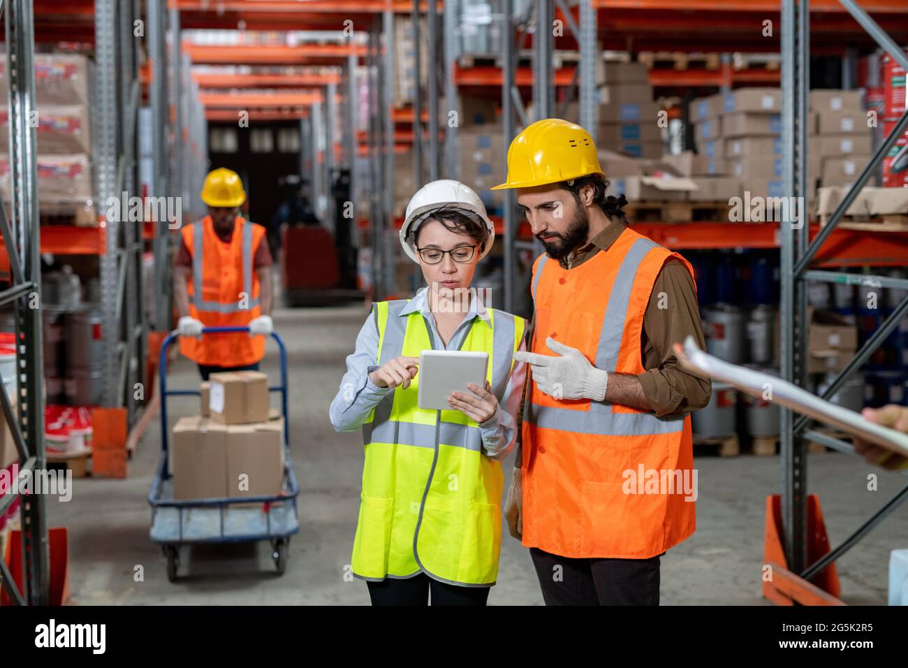 Two workers in hardhats scrolling through data in tablet Stock Photo