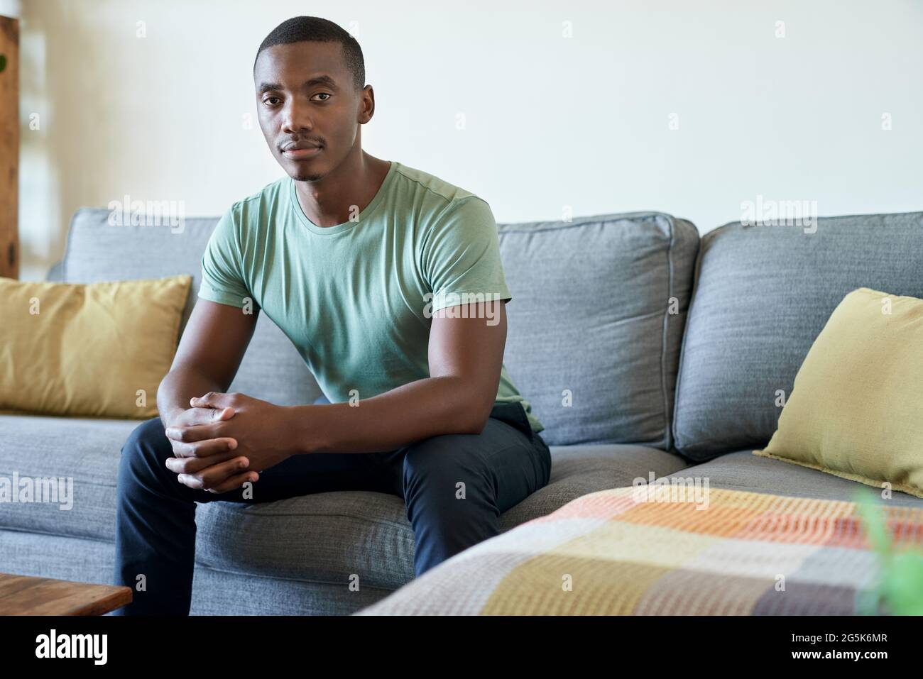 Young African man sitting on his living room sofa at home Stock Photo