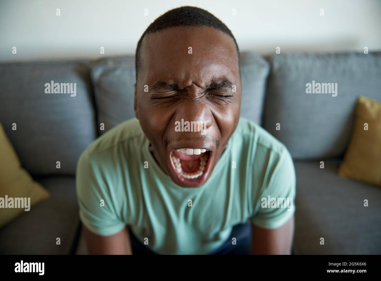 Young African man screaming in anguish at home Stock Photo