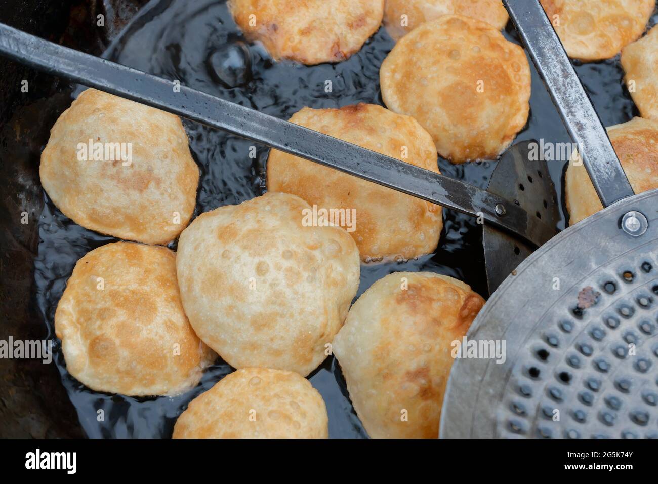 Many Kochuris are being fried in a frying pan. Kochuri, kachori of kachauri is a spicy snack, fried dumpling and a very popular street food in India. Stock Photo