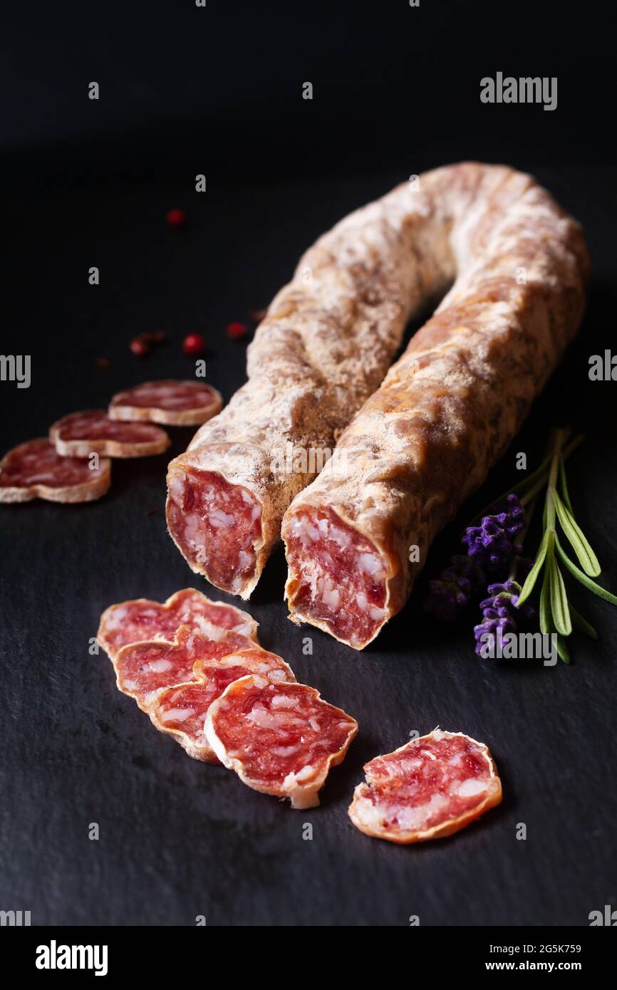 Food concept organic French Salami Saucisson on black slate board with