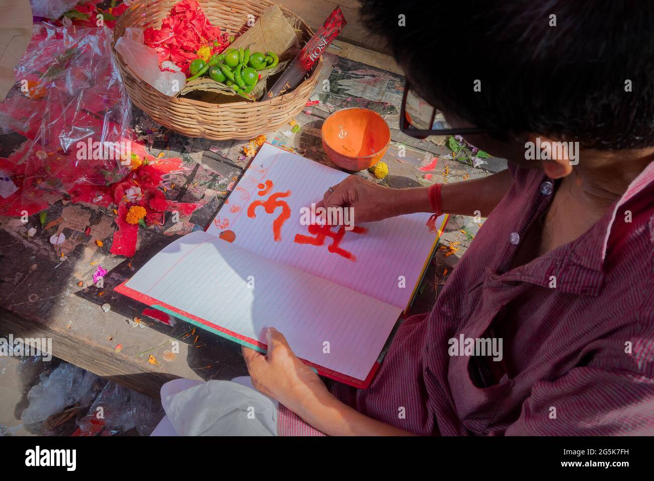 Kalighat, Kolkata, West Bengal, India - April 15th 2019 : Hindu priest drawing auspicious religious signs, on front pages of new accounts book for sta Stock Photo