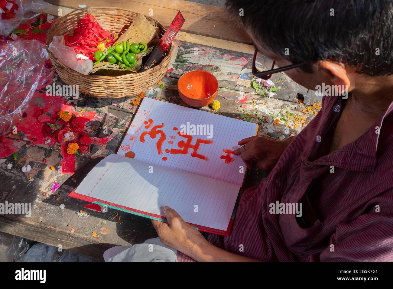 Kalighat, Kolkata, West Bengal, India - April 15th 2019 : Hindu priest drawing auspicious religious signs, on front pages of new accounts book for sta Stock Photo