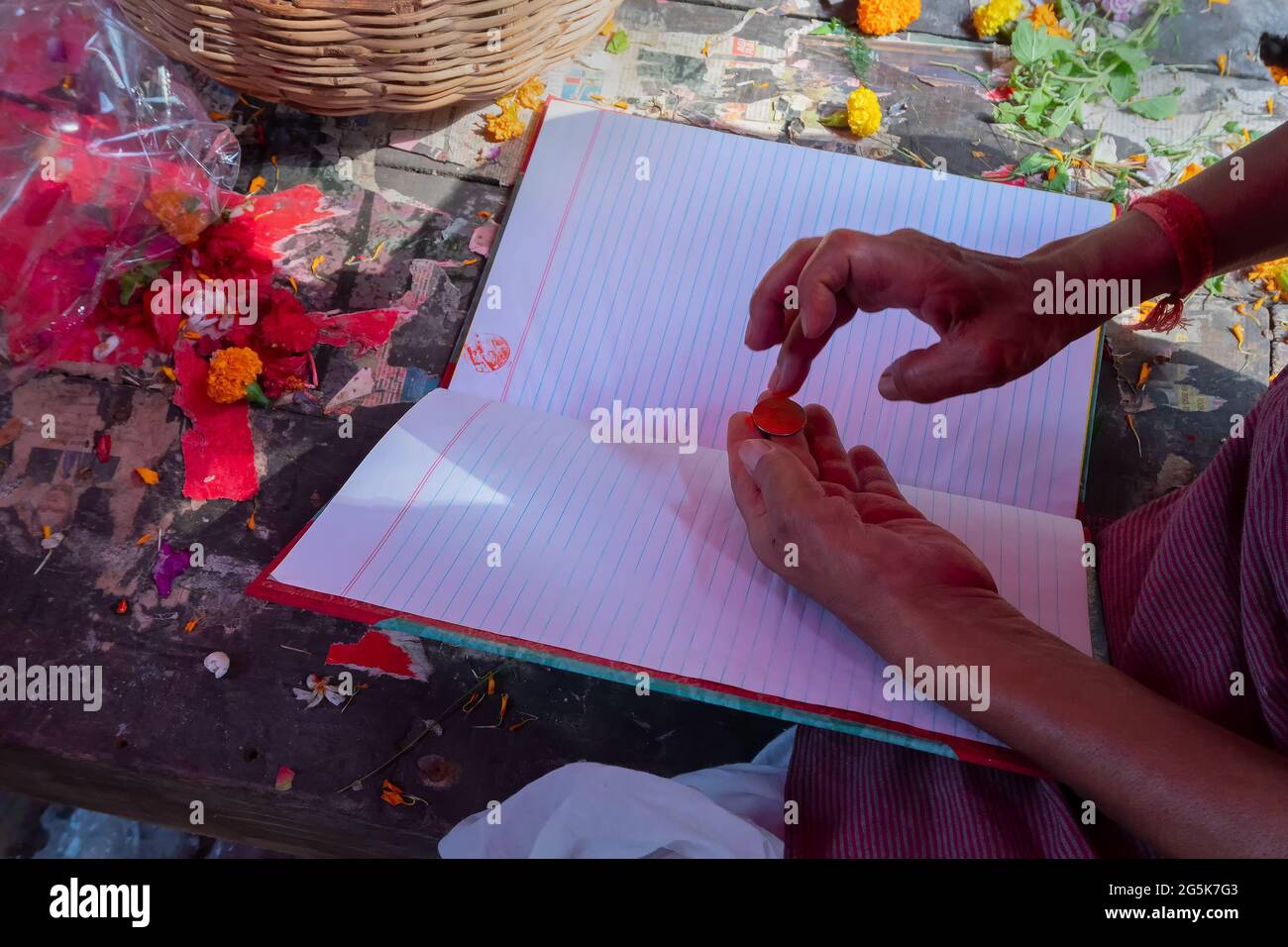 Kalighat, Kolkata, West Bengal, India - April 15th 2019 : Bengali Hindu priest painting auspicious religious sign using a painted coin, on top of new Stock Photo