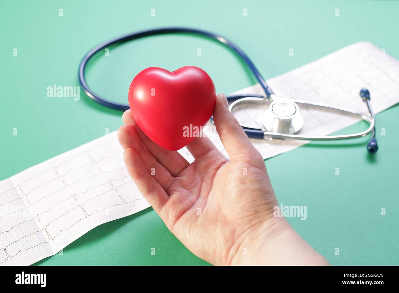 Doctor's hand with medical stethoscope heart and cardiogram on green ...