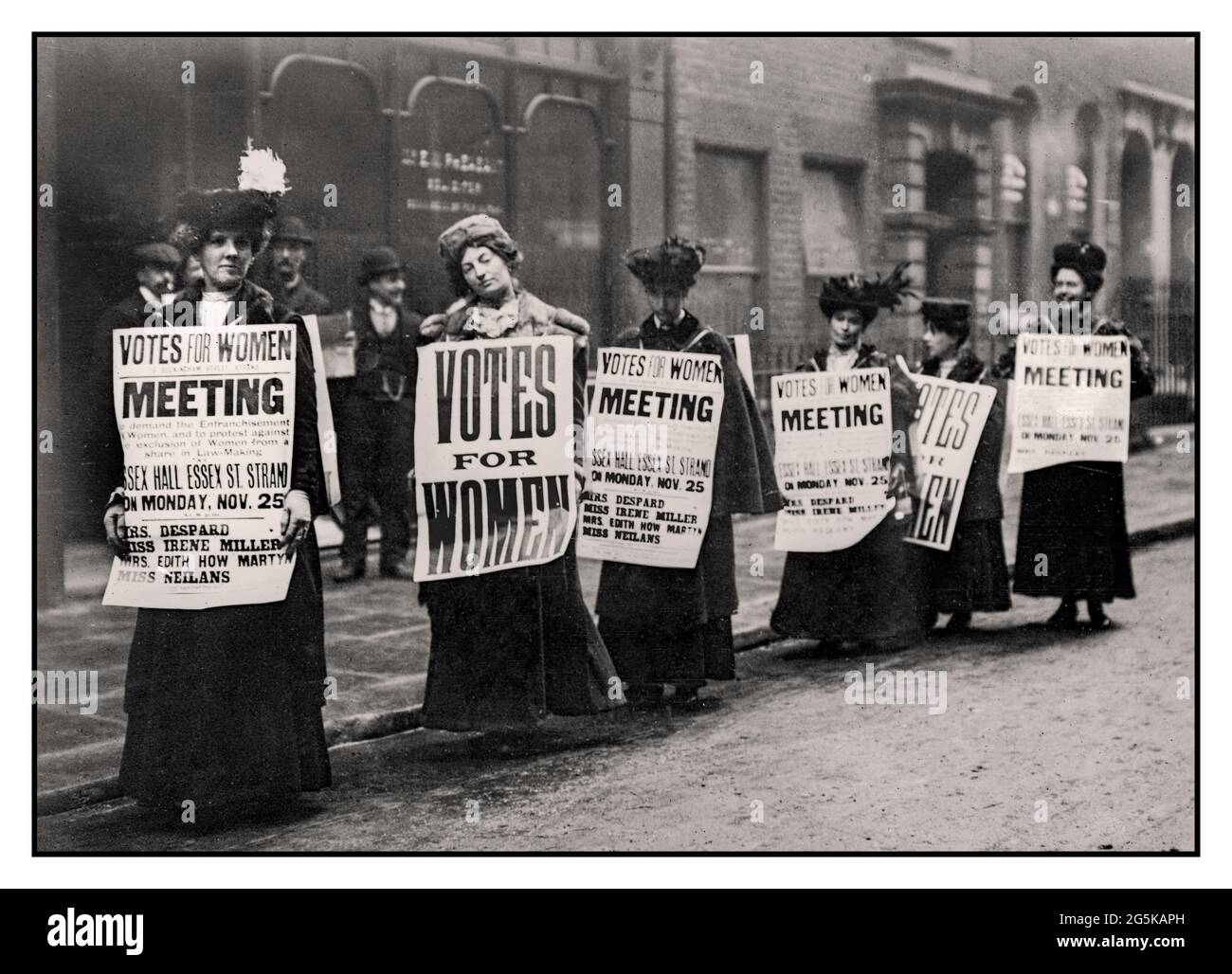SUFFRAGE 1900’s London UK Suffragettes, campaigning holding posters in London promoting and advertising British Suffrage ‘Meeting’’  ‘Votes for Women’ at Essex Hall Essex Street Strand London UK Stock Photo