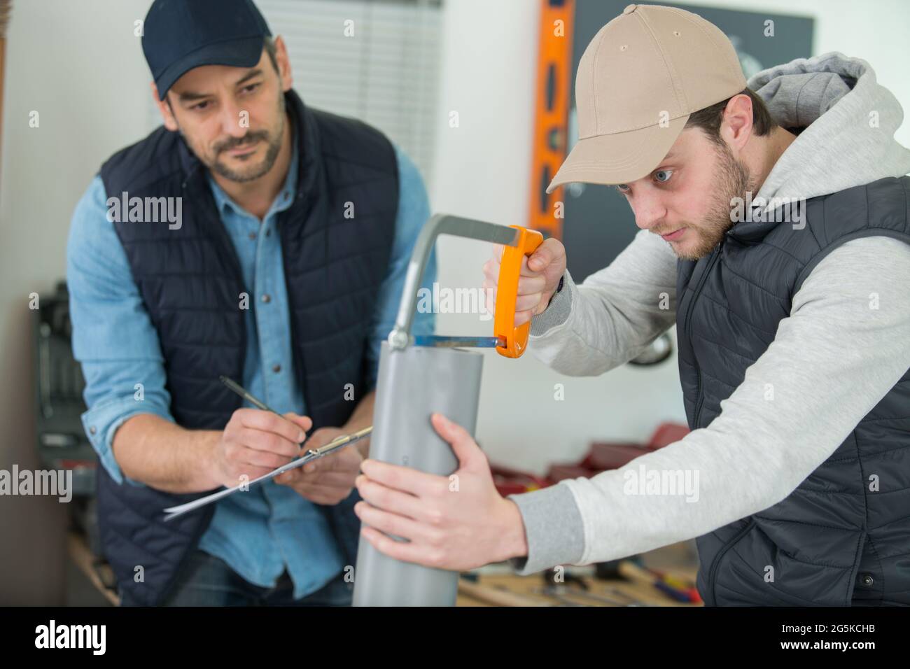 plumber checking apprentice cutting pvc pipe with a saw Stock Photo Alamy