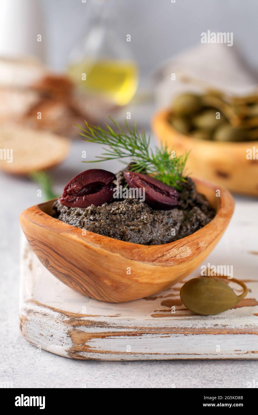 Black Tapenade or tapas, traditional Provence dish or dip with olives and basil on an old wooden table background. Selective focus. Top view Stock Photo