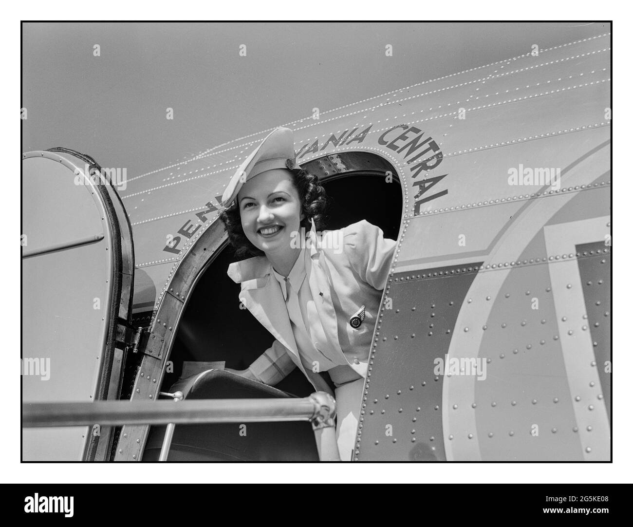 1940's airline crew air hostess flight attendant in uniform with welcoming smile at the entrance door to a DC3 Pennsylvania Central Airline aircraft. Municipal airport, Washington, D.C.by Jack Delano photographer LOC War administration FSA/OWI  1941 July. United States--District of Columbia--Washington (D.C Stock Photo