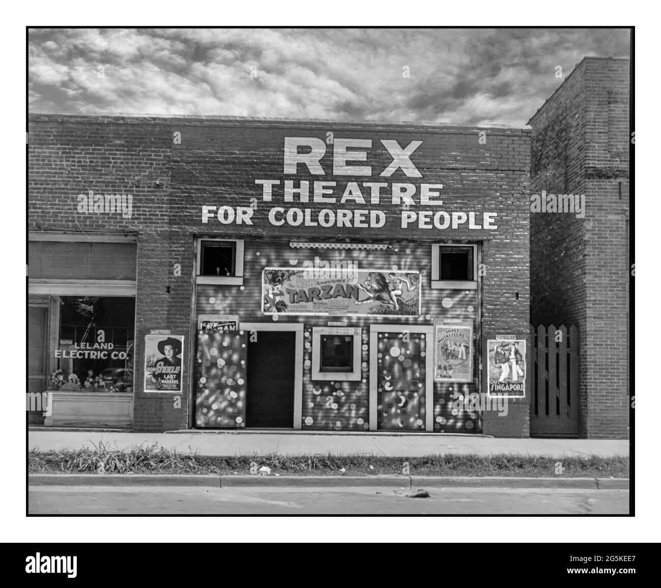 'REX THEATER FOR COLORED PEOPLE'  1930's Racist Racial divide division segregation sign USA with low rise small brick building Theatre in Leland, Mississippi 'for colored people' by Dorothea Lange, photographer 1937 June. Stock Photo