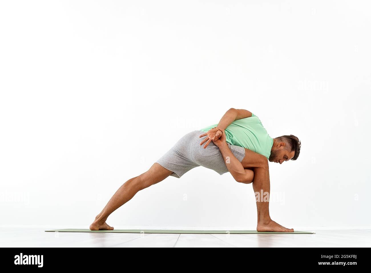 back view of sporty man practicing yoga in yoga class, making