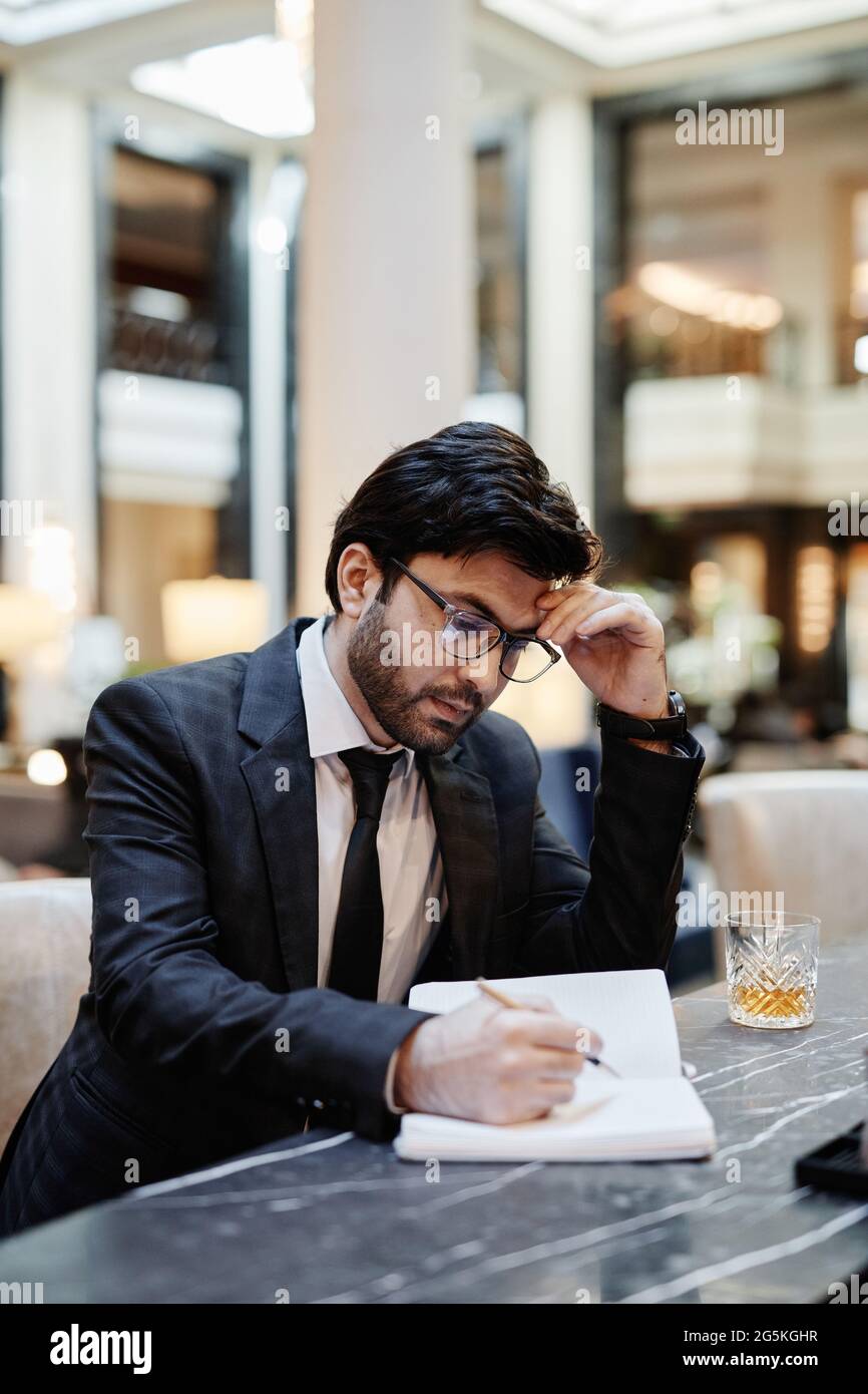 Vertical portrait of successful Middle-Eastern businessman working in hotel lobby during business trip Stock Photo