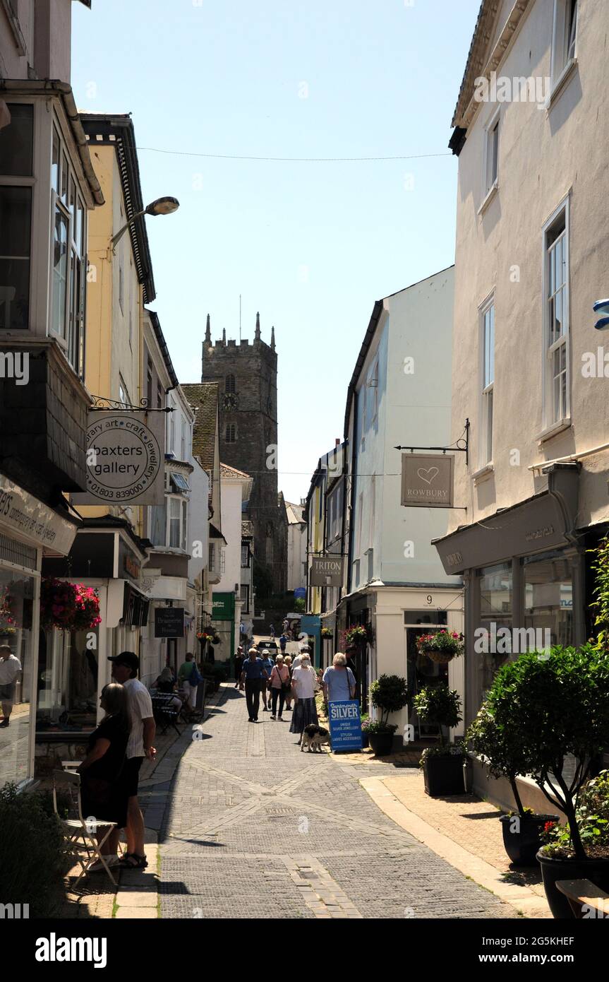 The shops along Foss Street in the Devon town of Dartmouth with the church of St Saviour's in the background. Stock Photo