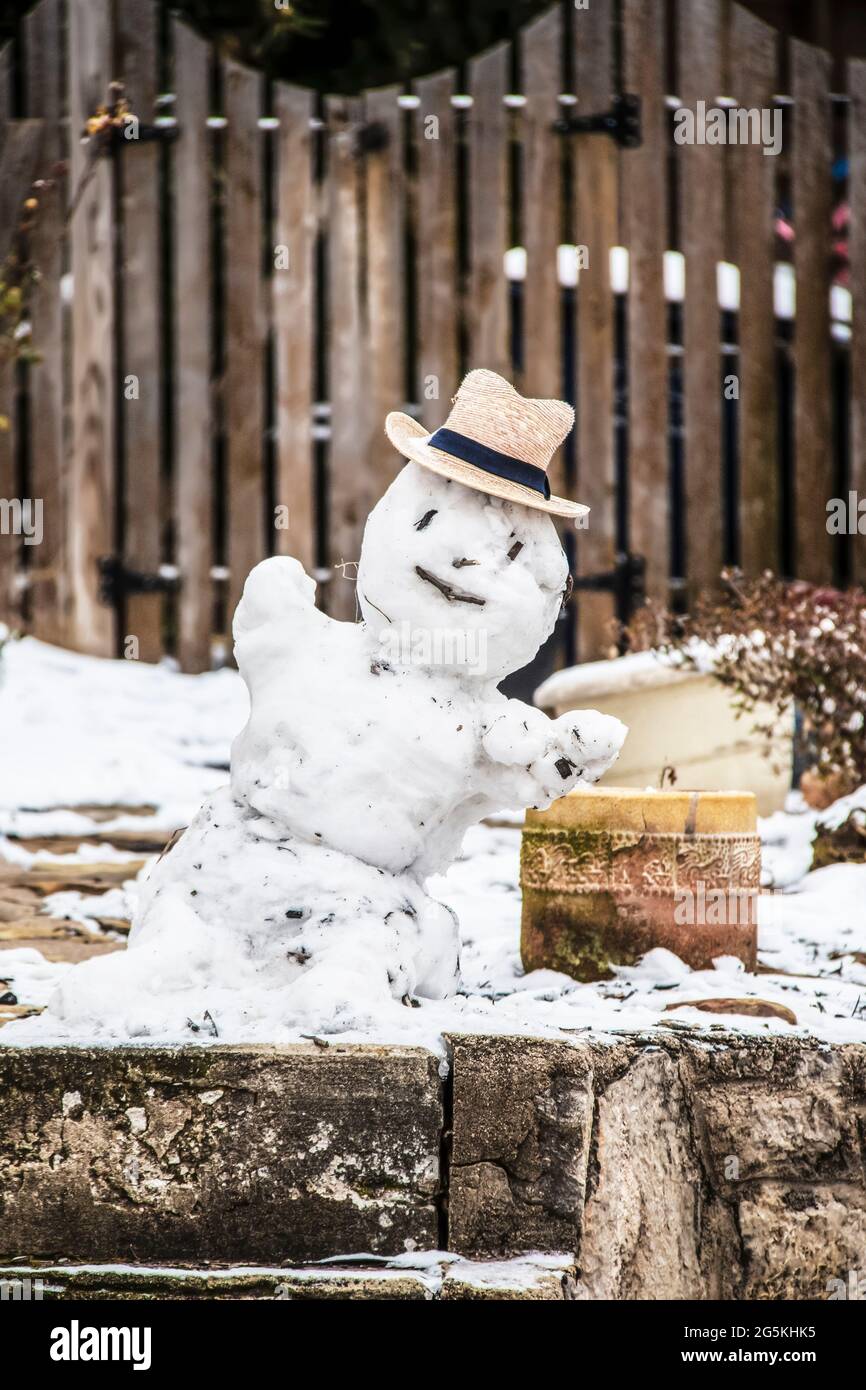 Small snowman in a straw hat in front of wooden fence - Selective focus Stock Photo