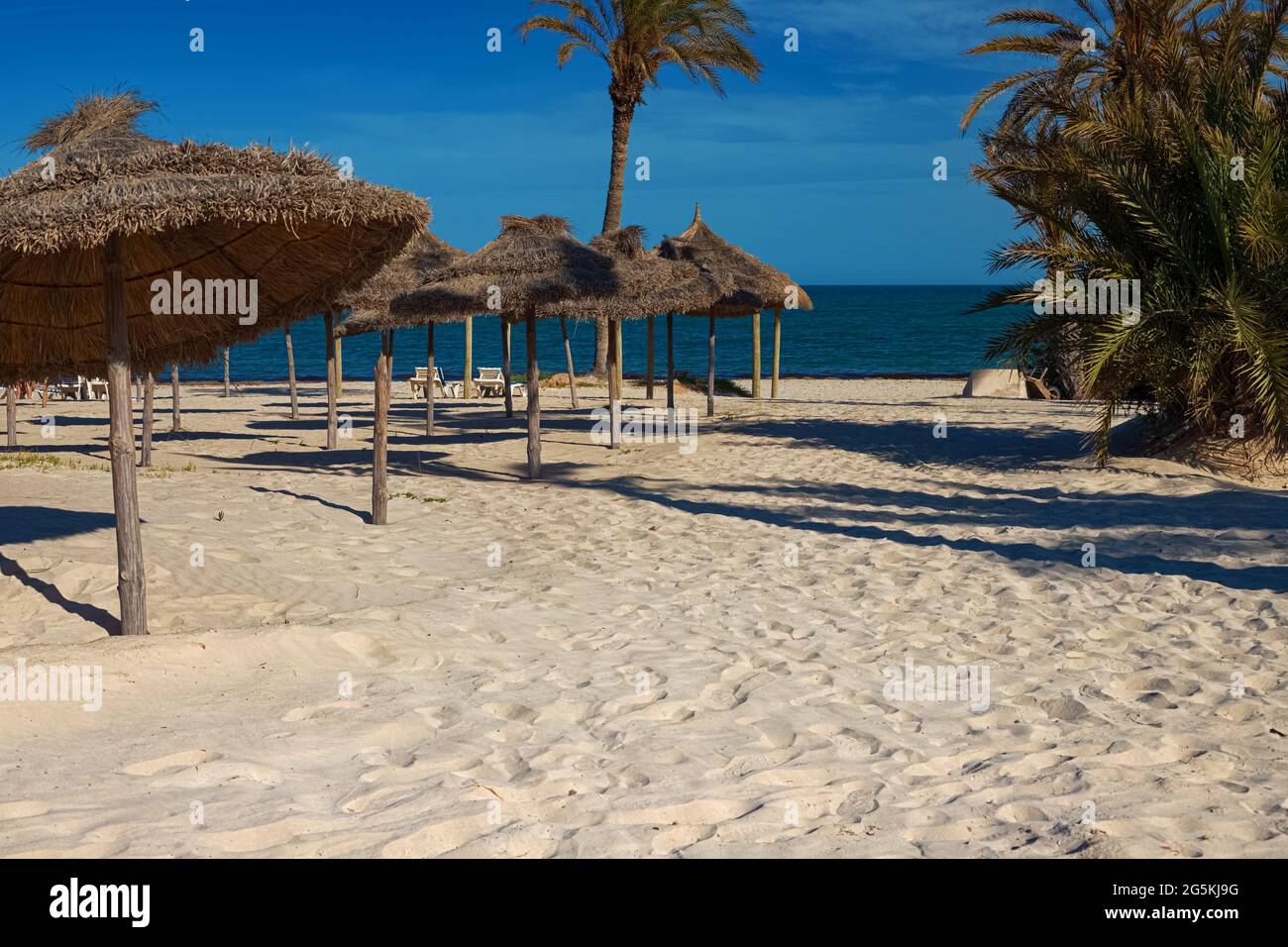 View of the white sand beach and parasols on the Mediterranean coast with birch water. Stock Photo