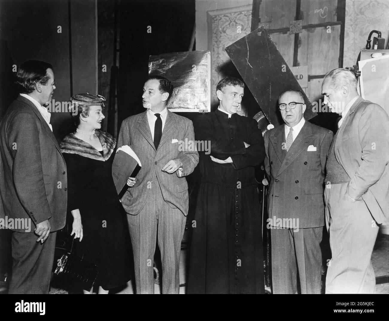 Director ROBERT HAMER JOAN GREENWOOD Set Visitor identified as Mr. LIPSKIN ALEC GUINNESS Set Visitor identified as Mr. McCONVILLE and Producer PAUL MOSS on set candid at Riverside Studios in Hammersmith, London during filming of FATHER BROWN 1954 director ROBERT HAMER from stories by G.K. Chesterton screenplay Robert Hamer and Thelma Schnee Facet Productions / Columbia Pictures Corporation Stock Photo