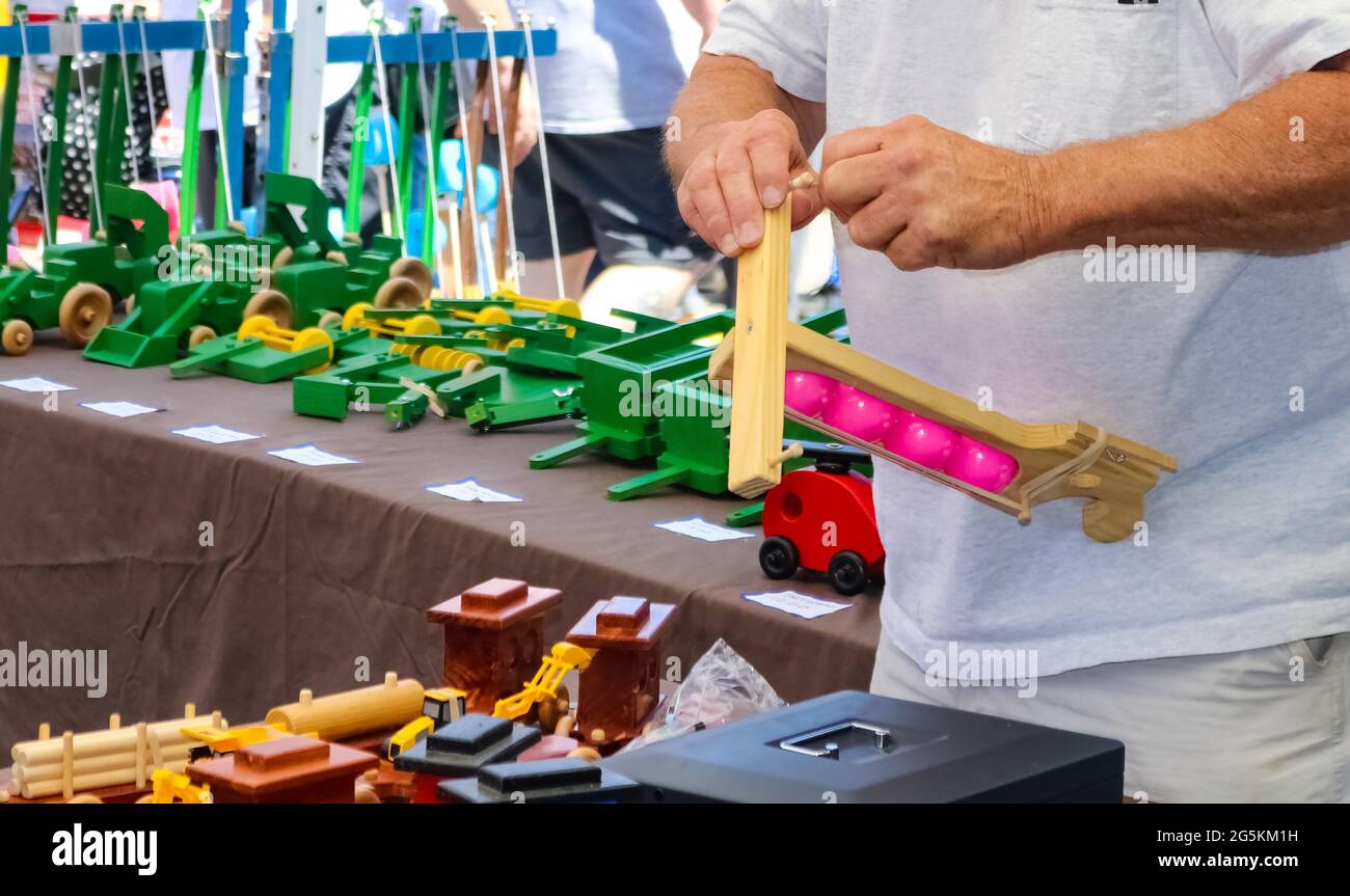 Toymakers hands putting together a wooden toy in a booth at out outside festival Stock Photo