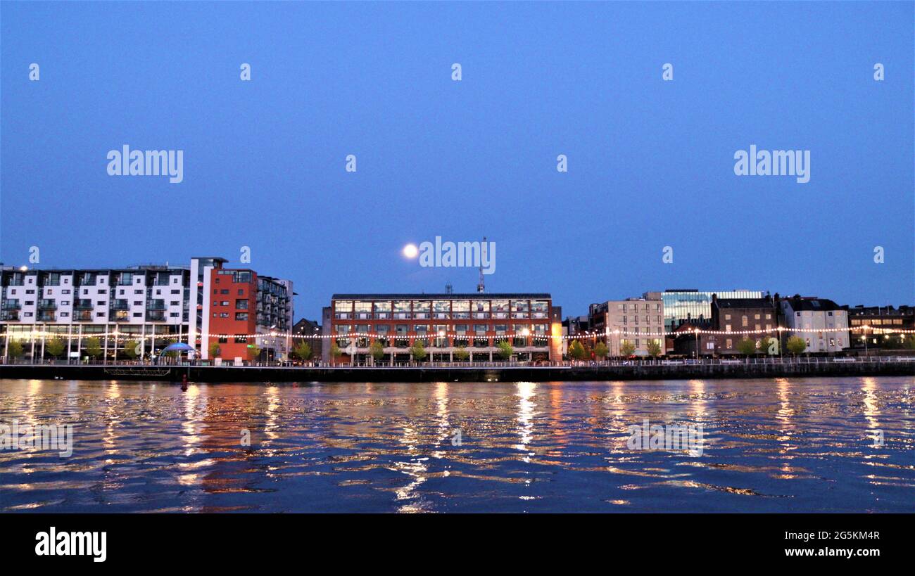 calm dusk evening in the town reflection on the water, still city at night, moon light reflected on the water. Stock Photo