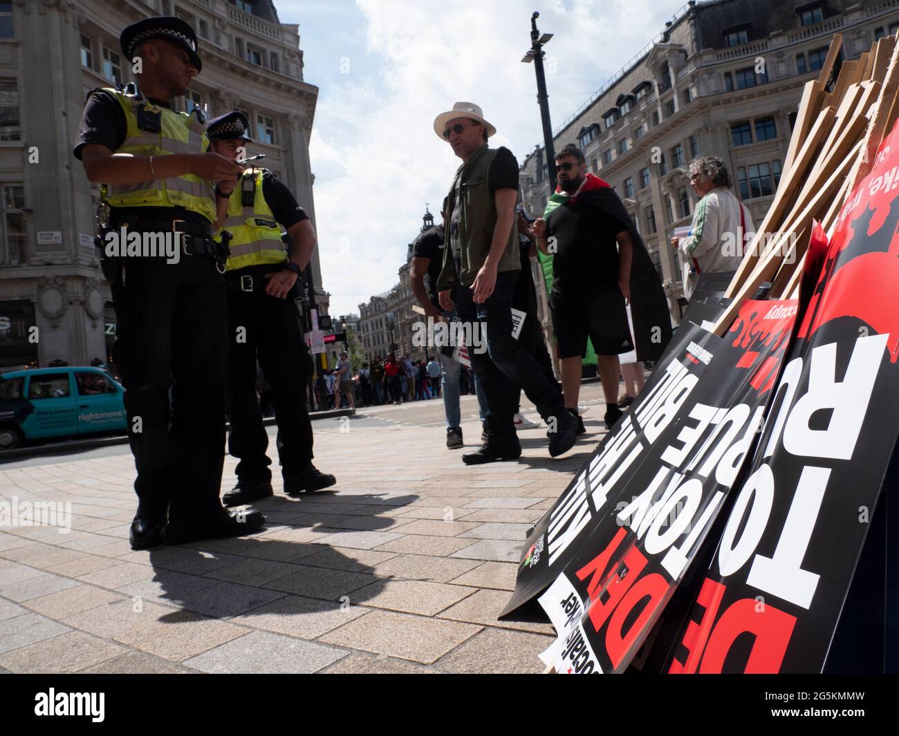 London protests, Activists protest in Central London at the People's Assembly National Demonstration, Police officers chat with protesters with Defy Tory rule placards made by socialist worker party in foreground Stock Photo