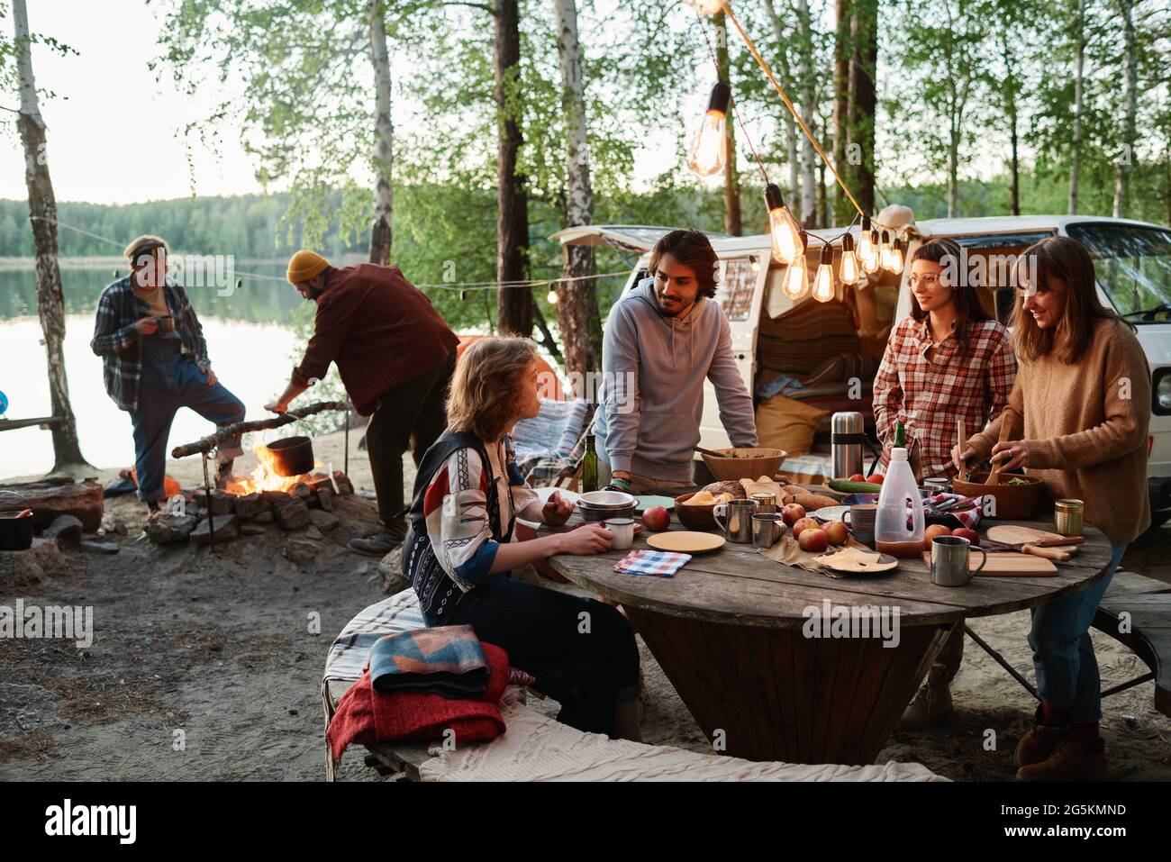 Group of friends eating and talking together on a picnic in the forest Stock Photo