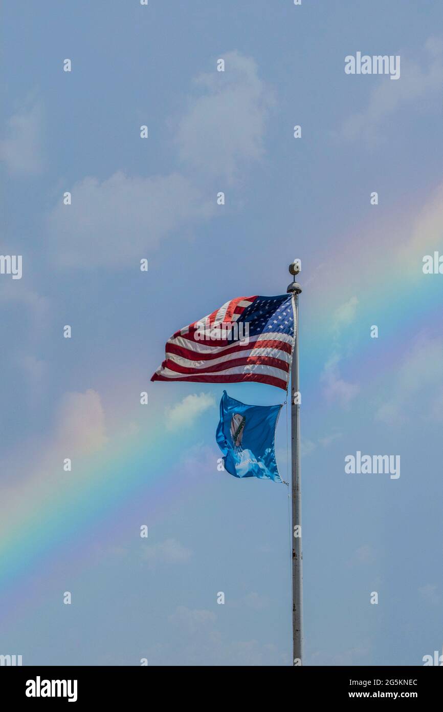 United States and Oklahoma flags flying high in front of rainbow sky with a few clouds Stock Photo