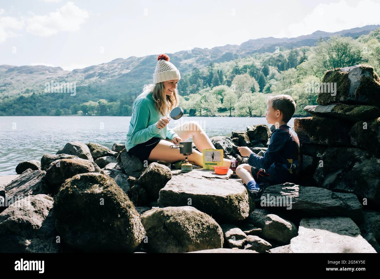 mom cooking on a portable cooker whilst camping with her son Stock Photo
