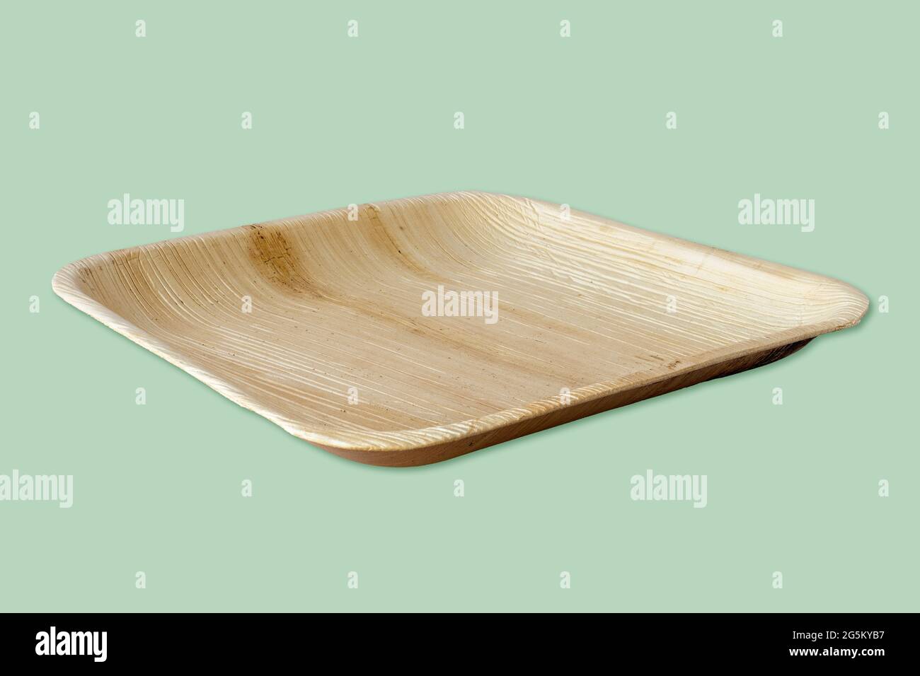Eco-friendly and sustainable palm leaf plate, isolated on green background. Plastic free, natural disposable and biodegradable tableware. Stock Photo