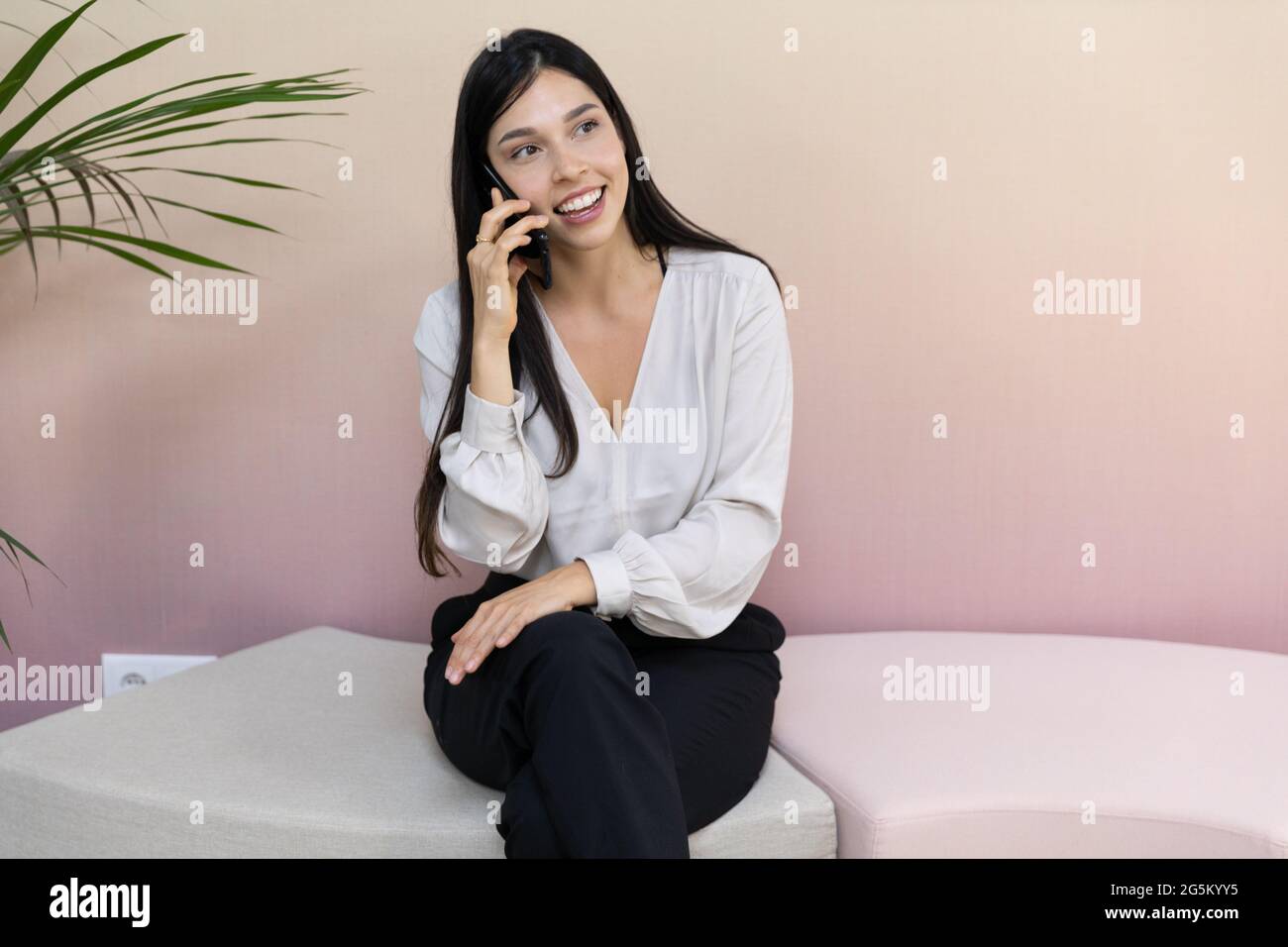 Pretty business woman wearing formal clothes sitting in the office and talking on the phone. Stock Photo