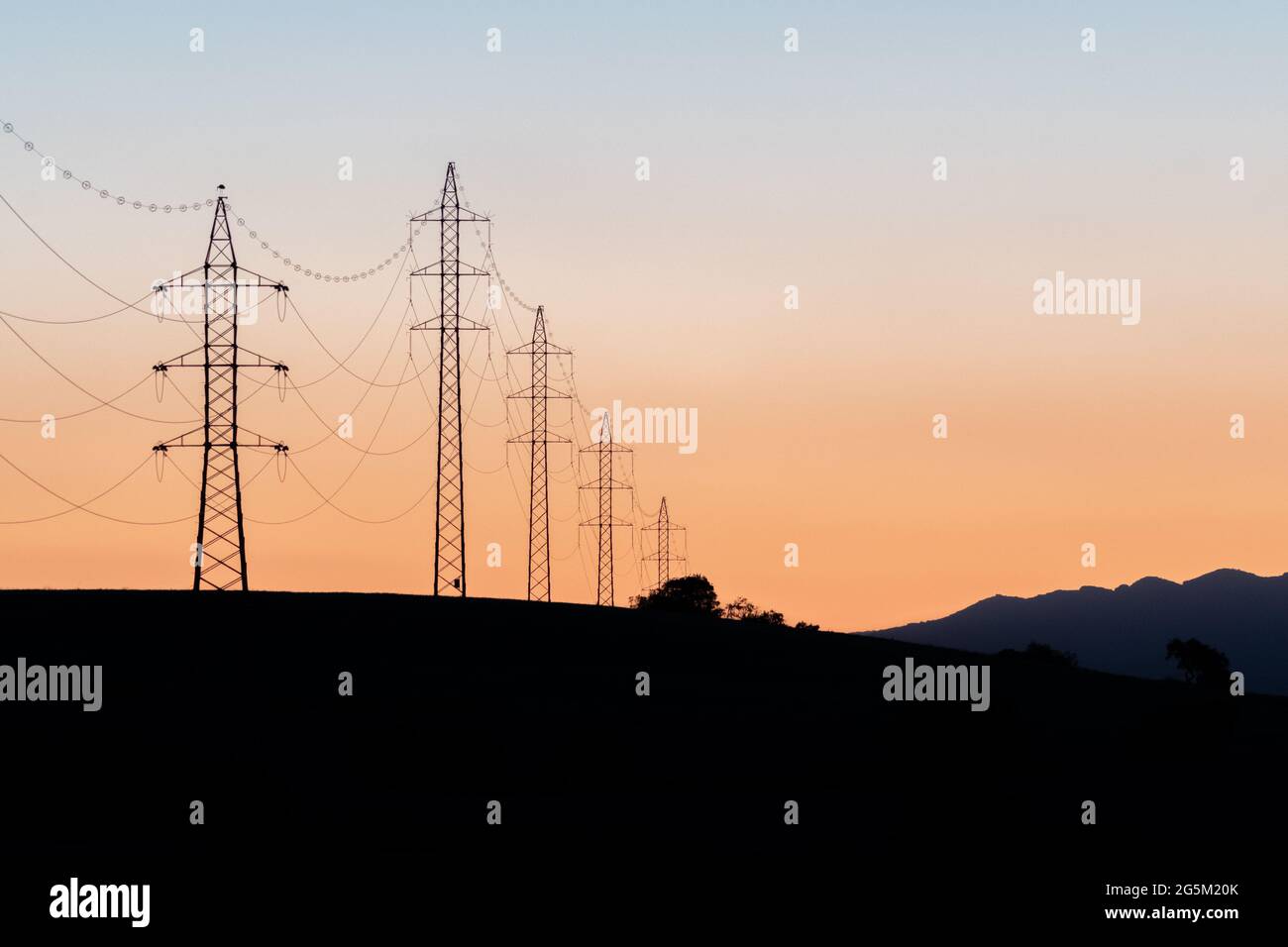 Towers of electricity over mountains at sunset. Silhouettes of power ...
