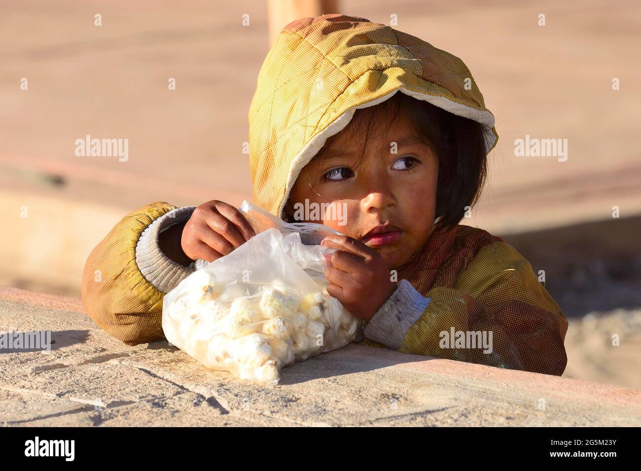 Child nibbling a snack of corn, Chinchero, Cusco region, Urubamba province, Peru, South America Stock Photo