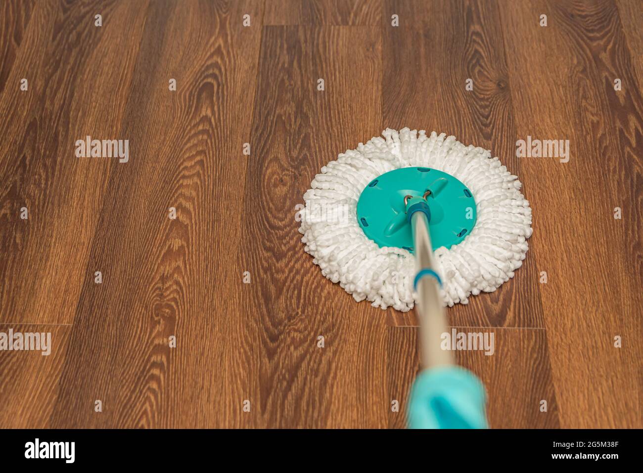 Floor cleaning and disinfection, house wet cleaning. Washing vinyl brown floor with a round mop, house cleaning, place for text Stock Photo