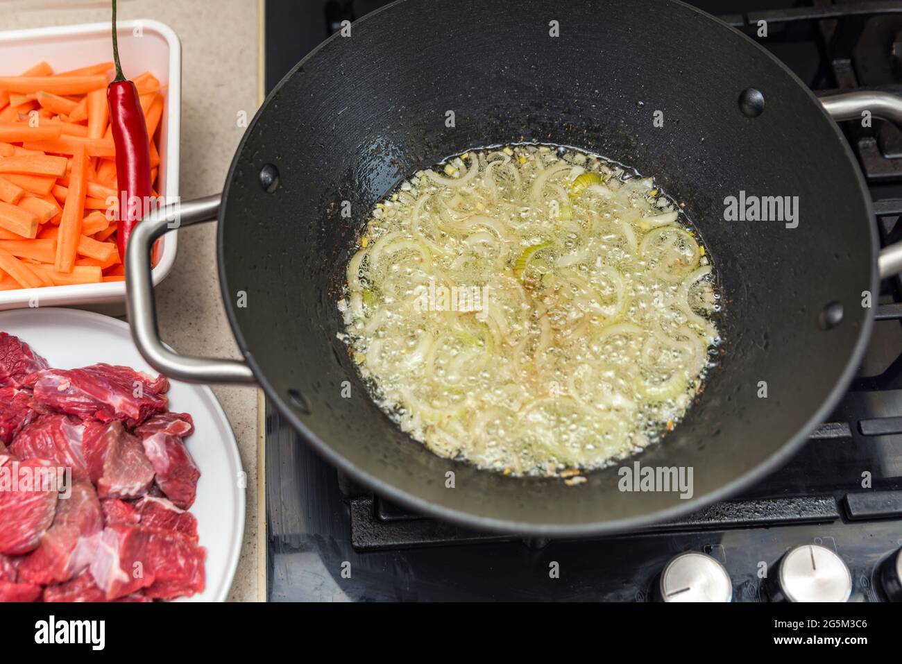 Cooking pilaf in a cauldron, a recipe for real pilaf.Fry onions in a cauldron for cooking pilaf, pour oil into a cauldron, a saucepan, before cooking. Stock Photo