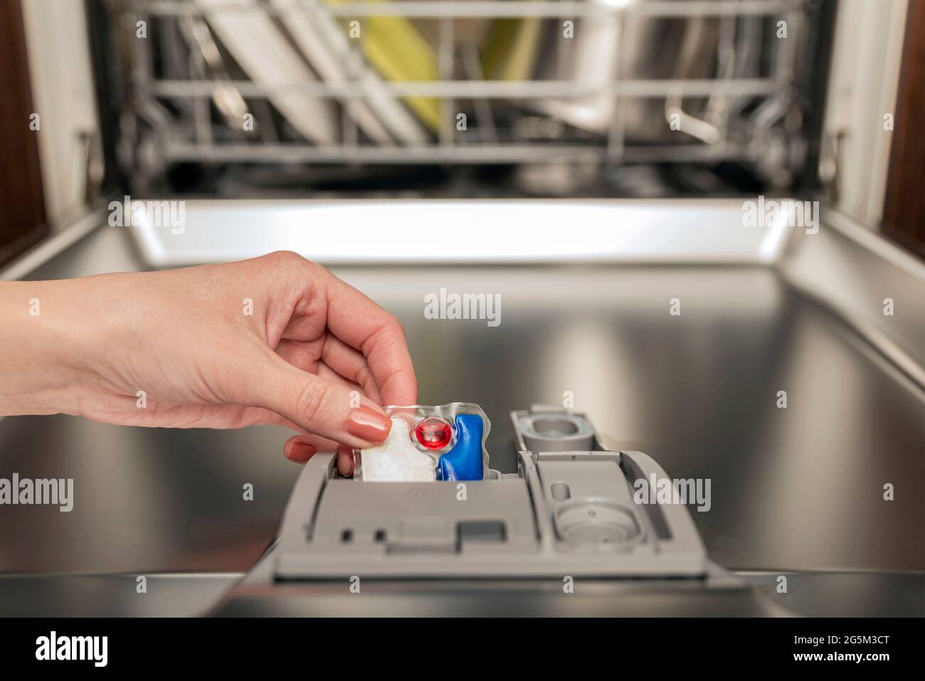 Dishwasher capsule, woman puts the capsule in the dishwasher before
