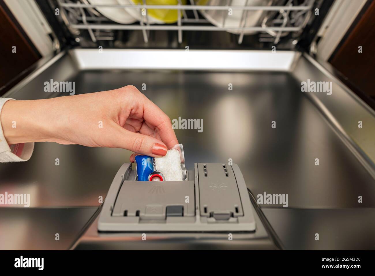 Dishwasher capsule, woman puts the capsule in the dishwasher before
