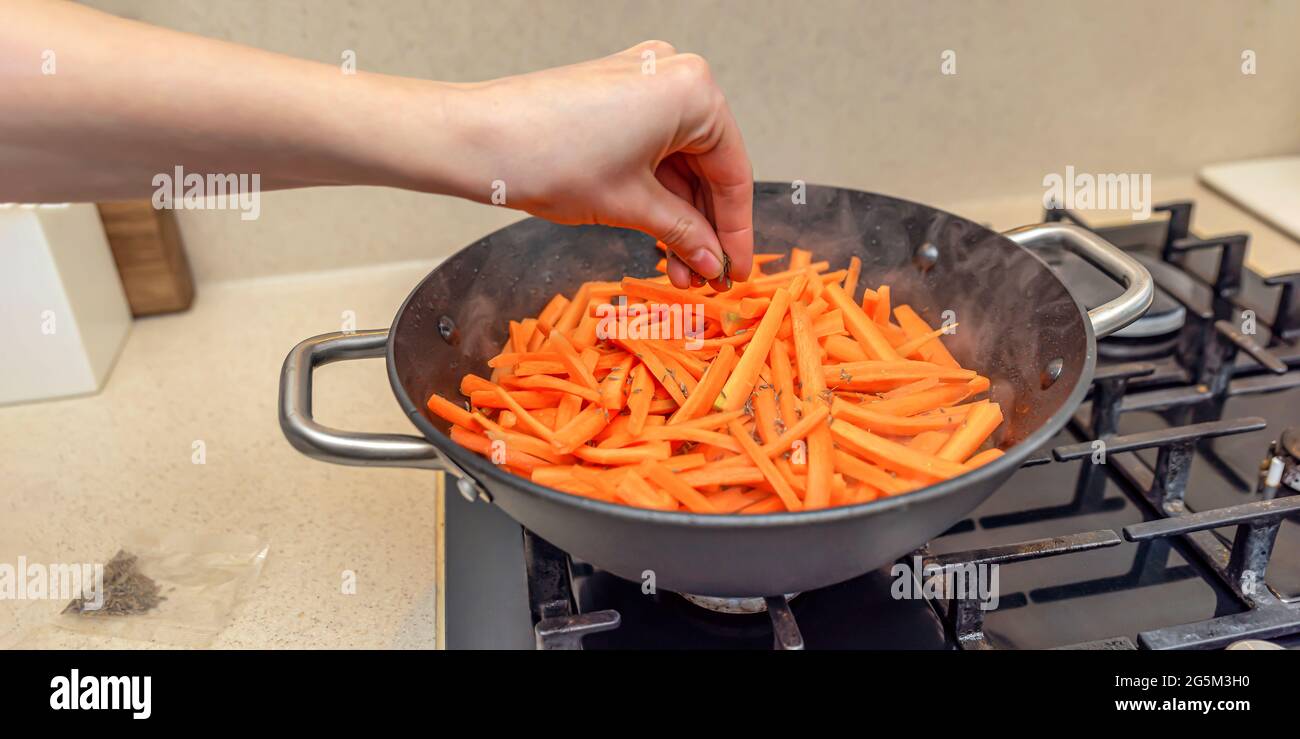 Cooking pilaf in a cauldron, a recipe for real pilaf. Sprinkle carrots with cumin, add spices to pilaf. Cooking pilaf at home Stock Photo