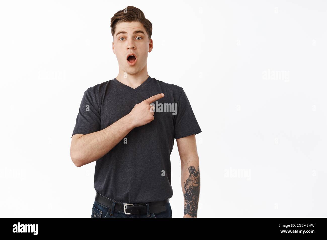 Portrait of impressed 25s young man pointing at upper right corner