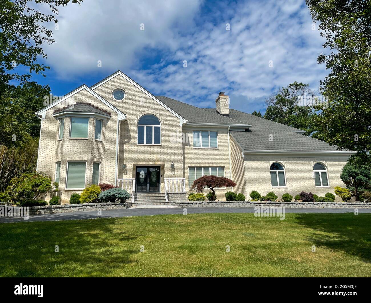 Single family suburban house made of light brick in an affluent neighborhood in New Jersey. Stock Photo