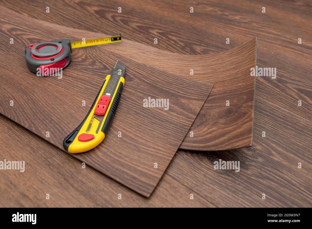 Vinyl flooring installation. Easy installation and cutting with a knife,  Master cuts vinyl plank before installation, brown heated floor. Copy space  Stock Photo - Alamy