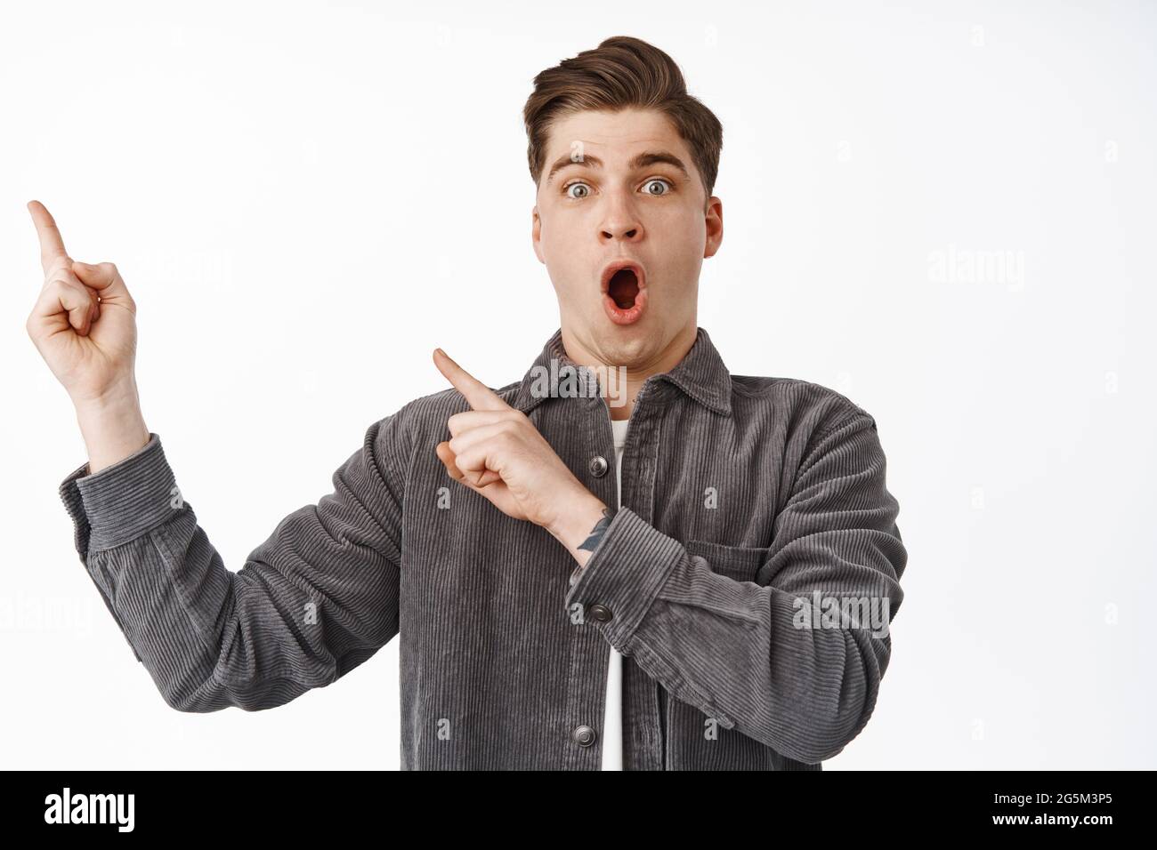 Surprised modern guy drops jaw, points at upper left corner with