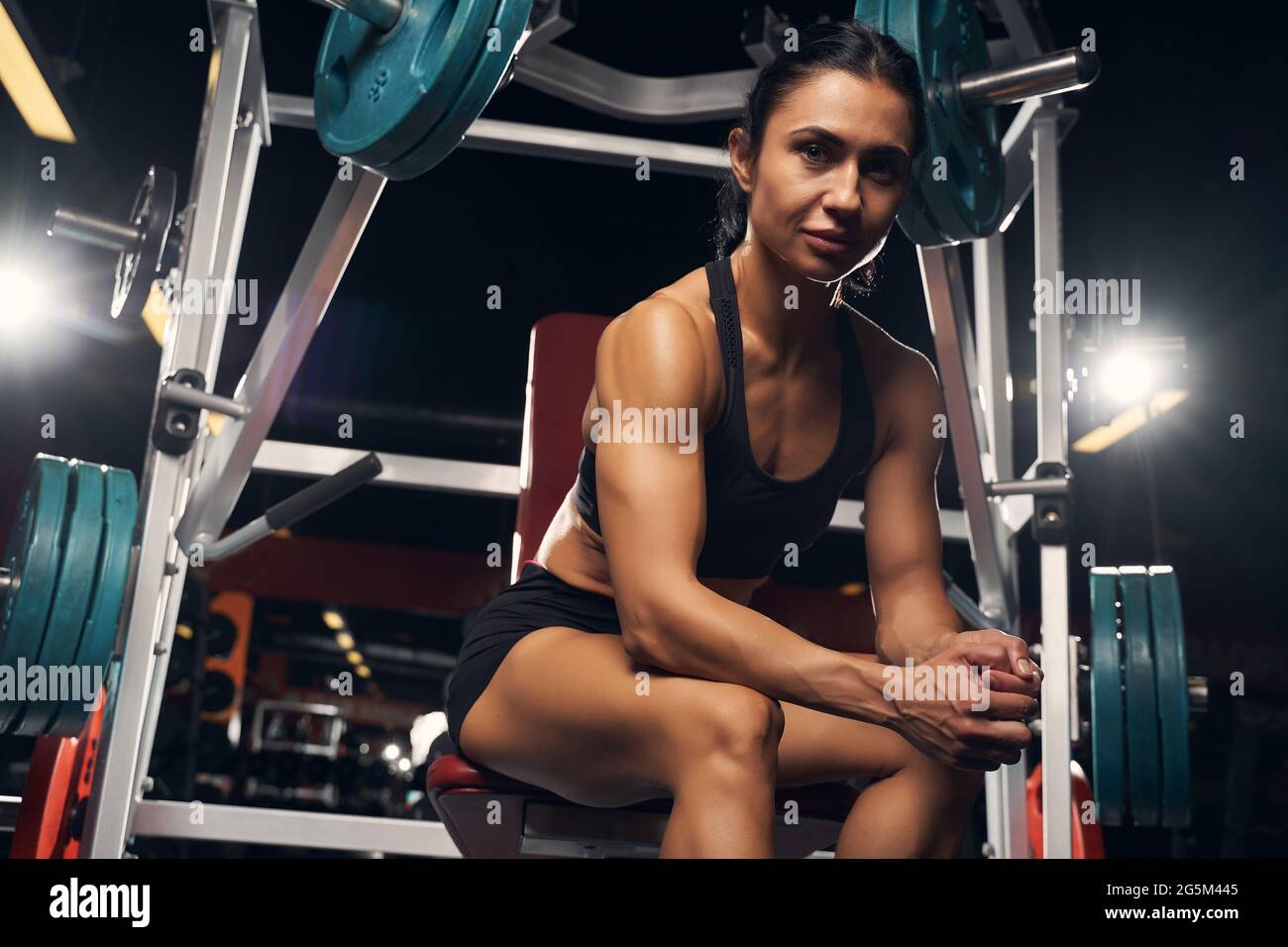 Muscled woman sitting at the piece of gym equipment Stock Photo - Alamy